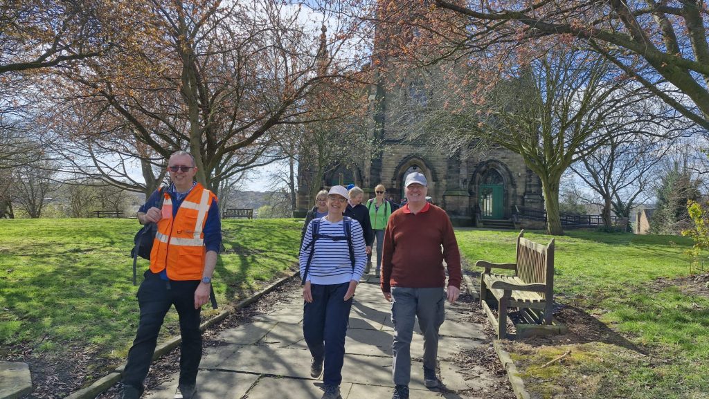 A group of walkers walk down a path from St Mary's Greasbrough Chruch