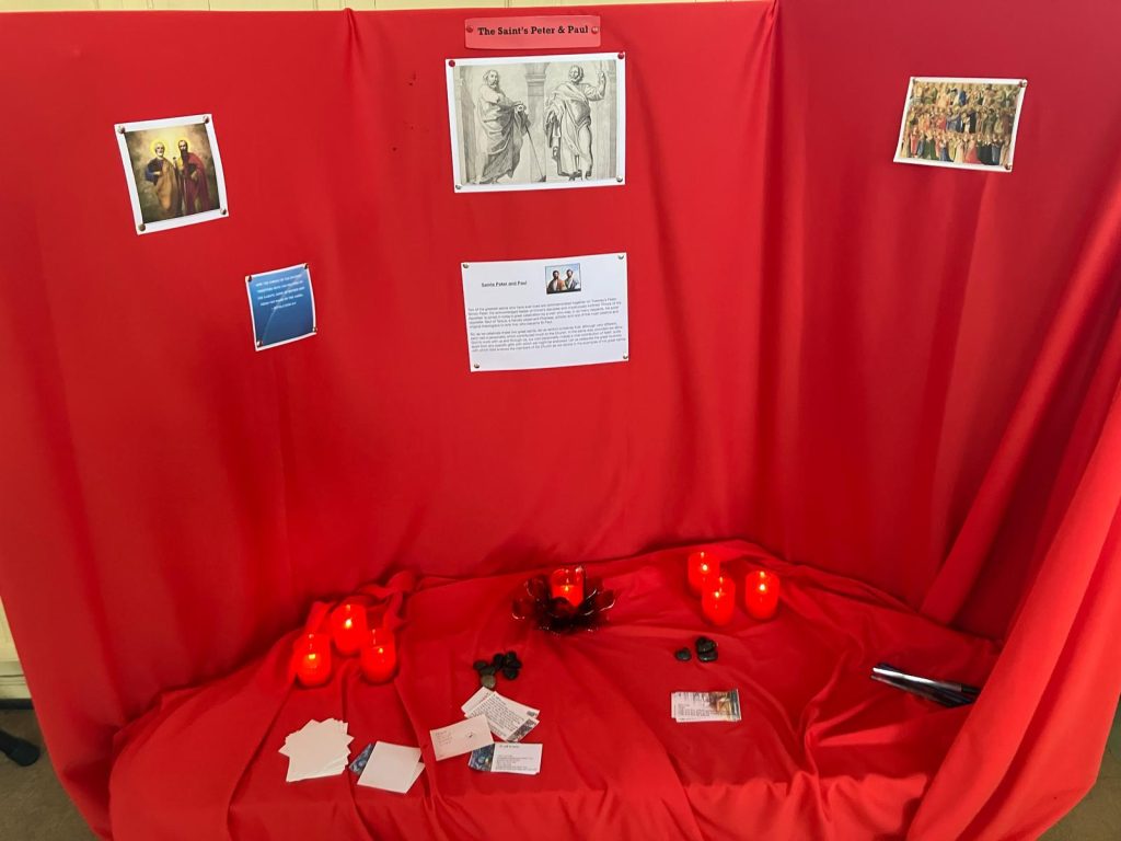 All images show photos and wording on a red background table. The first image show a reflection on St Peter and St Paul. The second image features small stones and cards encouraging prayers for oneself. The third image has candles and different prompts for prayers for the world.