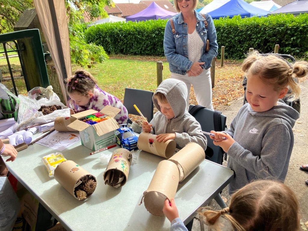 A boy sits at a table, drawing on a cardboard tube, which will become a bug hotel